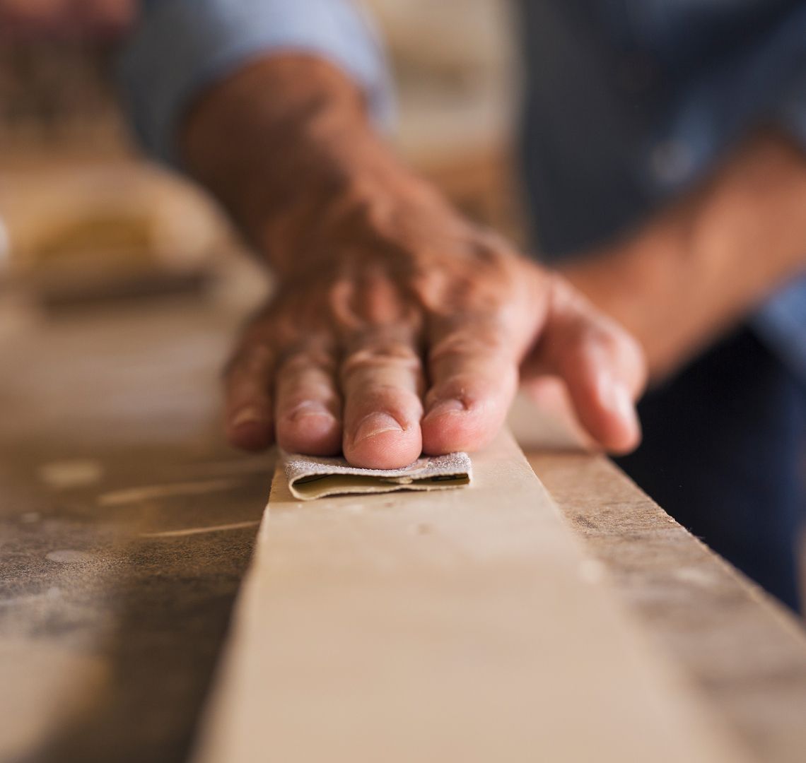Tischler der mit Sandpapier über Holz schleift